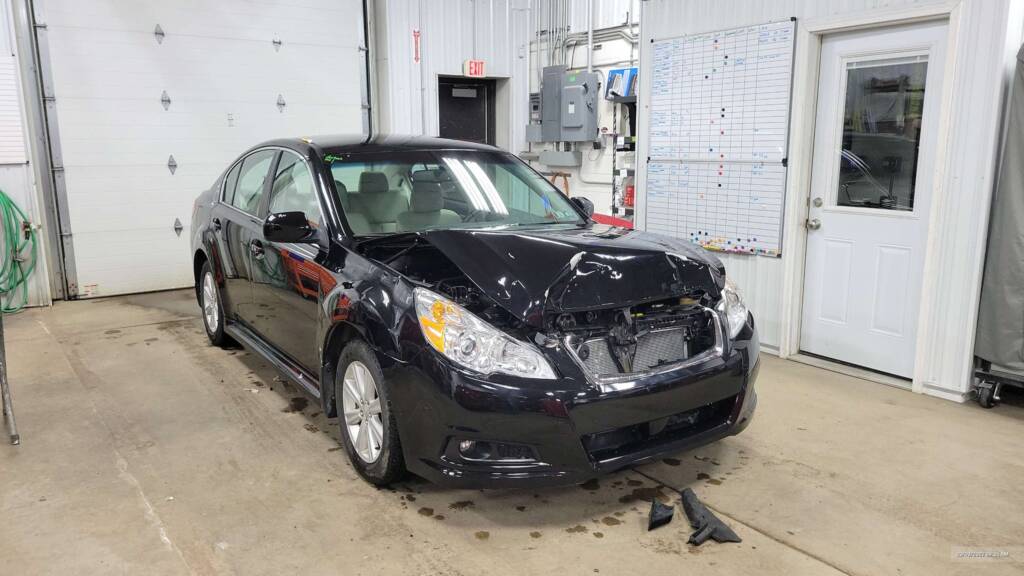 A damaged black Subaru Legacy taken into Eldred Collision for full auto repair.