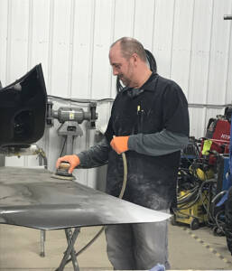 Eldred Collision does buffing on a car hood.