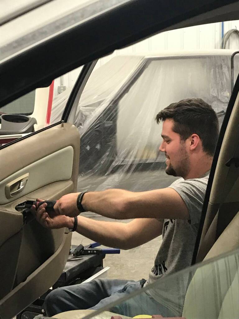 A skill mechanic at Eldred Collision repairs a car door.